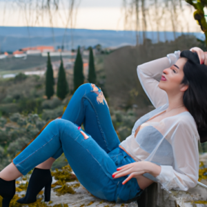 A woman in a relaxed pose, with a tranquil landscape in the background.