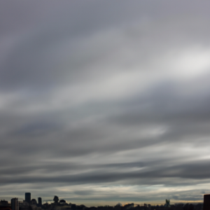 A sky filled with dark grey clouds and a silhouette of a city skyline in the background.
